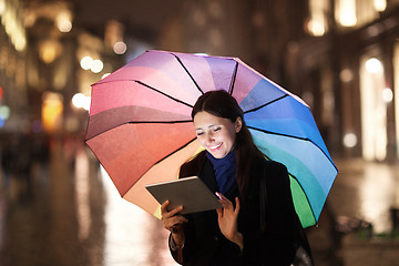 Image showing Woman using pad under umbrella in the evening city