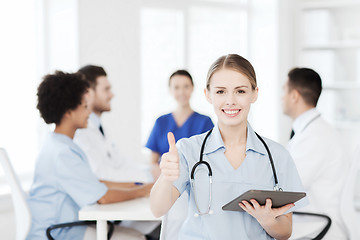 Image showing happy doctor with tablet pc over team at clinic