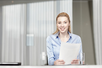 Image showing smiling woman holding papers in office