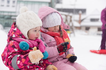 Image showing portrait of two little grils sitting together on sledges