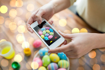 Image showing close up of hands with easter eggs and smartphone