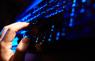 Image showing Man\'s hand typing on a blue keyboard.