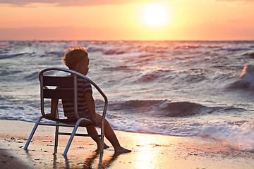 Image showing Little child looking at sunset sitting by the sea