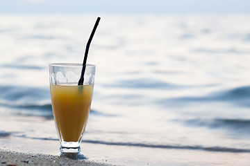 Image showing Glass of cocktail on beach near water