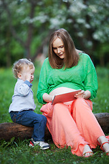 Image showing Pregnant mother with little son using touch pad in the park