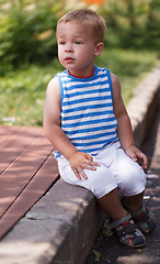 Image showing Cute boy sitting on the curb