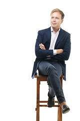 Image showing Young businessman sitting on high wooden chair