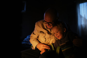 Image showing Grandfather hugs his grandson near fireplace