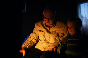 Image showing Grandfather and grandson near fire at home.