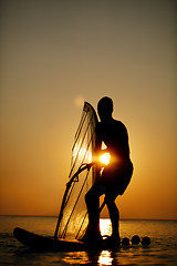 Image showing Man sailboarding at sunset