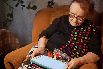 Image showing Elderly lady sitting in an chair using a tablet