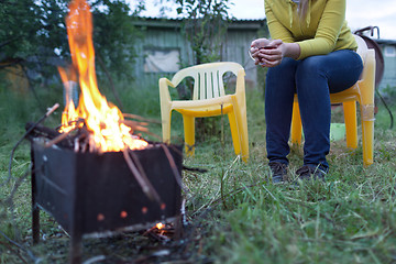 Image showing Woman with tea near the fire in yard