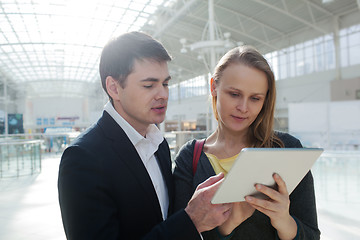 Image showing Young businesspeople with pad in shopping centre