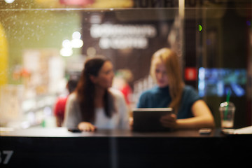 Image showing Two female friends using tablet PC in a cafe