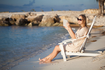 Image showing Woman with pad relaxing in chaise-lounge on the beach