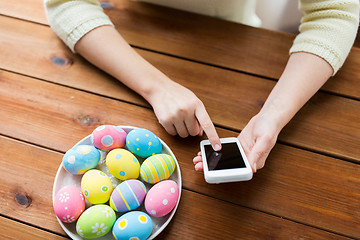 Image showing close up of hands with easter eggs and smartphone