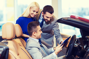 Image showing happy couple with car dealer in auto show or salon