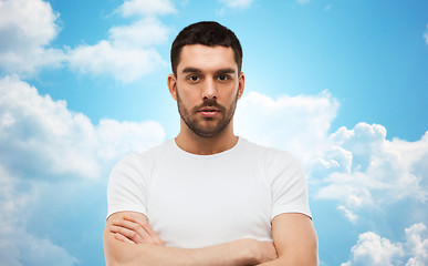 Image showing young man with crossed arms over blue sky