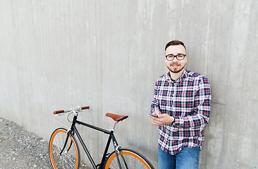 Image showing hipster man in earphones with smartphone and bike