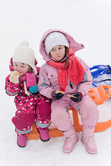 Image showing portrait of two little grils sitting together on sledges