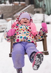 Image showing little girl at snowy winter day swing in park