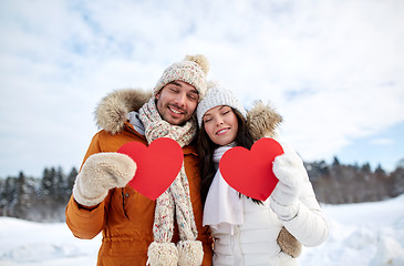 Image showing happy couple with red hearts over winter landscape