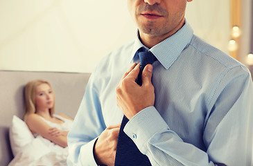 Image showing close up of man adjusting tie on neck in bedroom