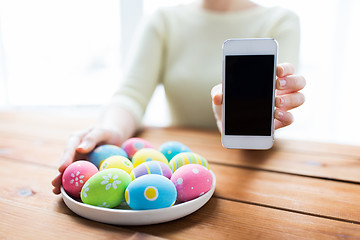 Image showing close up of hands with easter eggs and smartphone