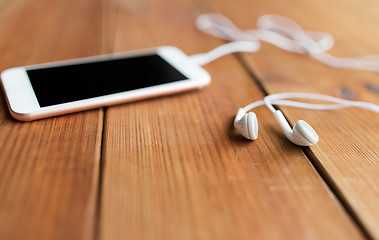 Image showing close up of blank smartphone and earphones on wood