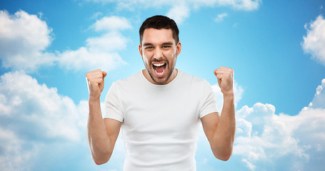 Image showing young man celebrating victory over blue sky