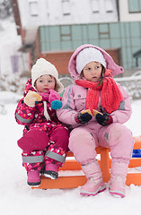 Image showing portrait of two little grils sitting together on sledges