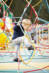 Image showing Happy little boy climbing on playground equipment