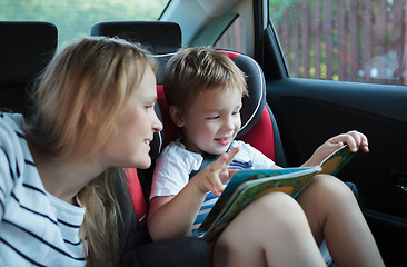 Image showing Mother and son with a book in the car