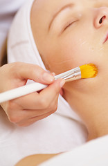 Image showing Woman being applied a facial mask