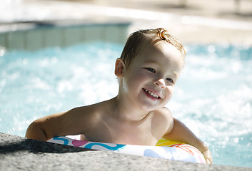 Image showing Kid learns to swim using a plastic water ring