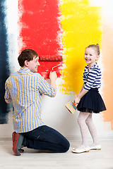 Image showing Happy girl painting wall with father