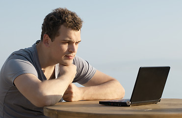 Image showing Man looking to the display of small laptop computer