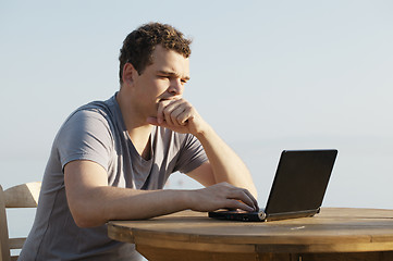 Image showing Man typing on a small laptop computer