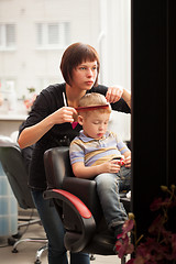 Image showing Little boy getting a haircut from hairdresser