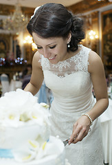 Image showing Smiling beautiful bride cutting the wedding cake