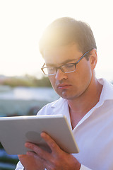 Image showing Young businessman deep at work with pad outdoor