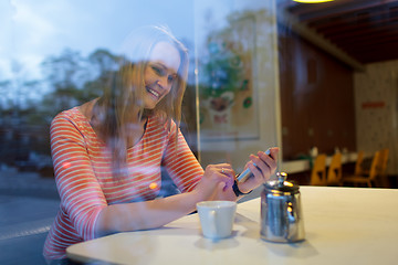 Image showing Young woman using a mobile phone in cafeteria