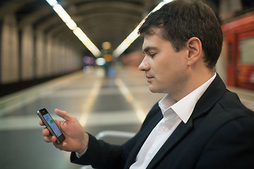 Image showing Young man reading sms on smartphone in underground