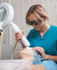 Image showing Cosmetician providing facial treatment with a laser