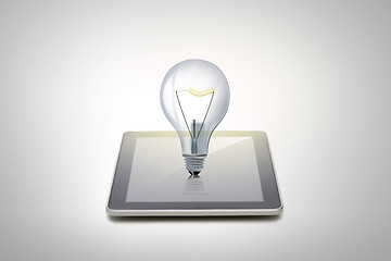 Image showing close up of tablet pc computer with light bulb