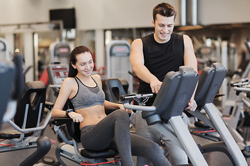 Image showing happy woman with trainer on exercise bike in gym