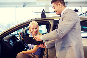 Image showing happy woman with car dealer in auto show or salon