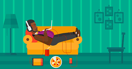 Image showing Man lying on sofa with many gadgets.