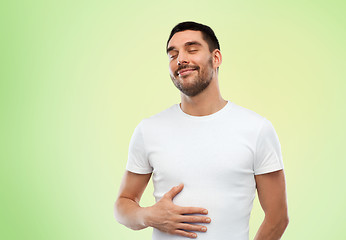 Image showing happy full man touching tummy over green 