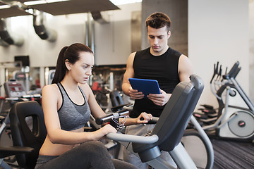 Image showing woman with trainer on exercise bike in gym